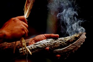 Sauge qui dégage sa fumée purifiante dans un grand coquillage à l'aide d'une plume